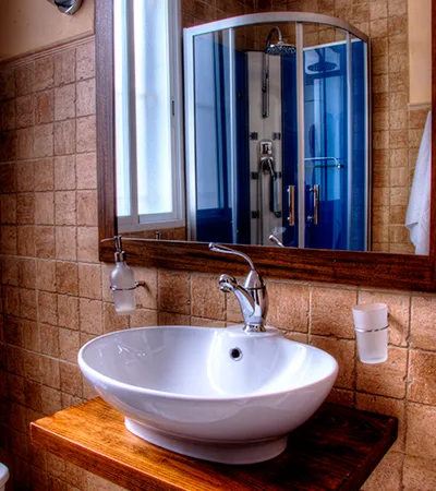 fotografía del baño, lavabo y espejo con reflejo de la cabina de ducha